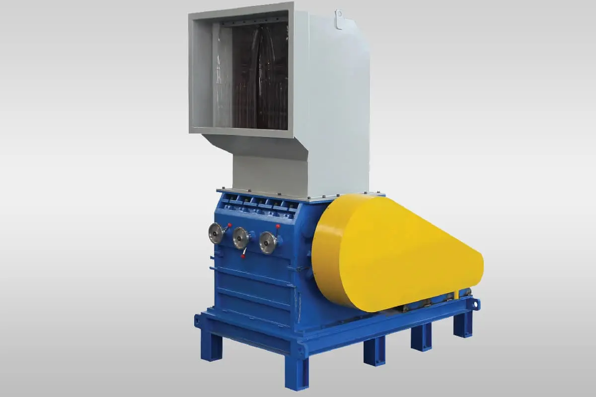 The image showcases an industrial shredder, specifically a plastic granulator. This machine is designed to break down large pieces of plastic into smaller flakes or granules, facilitating recycling, further processing, or disposal. Key Components and Function: Hopper: The gray, box-shaped component at the top is the hopper, where the plastic material to be shredded is fed into the machine. Cutting Chamber: Inside the machine, there is a cutting chamber containing rotating blades or knives that shred the plastic. Motor: An electric motor (not visible in the image) powers the rotating blades, providing the force necessary for the shredding process. Screen/Filter: A screen or filter within the cutting chamber controls the size of the output granules. Discharge Chute: The shredded plastic pieces are discharged through the yellow chute, typically leading to a collection bin or conveyor. Control Panel: The control panel, with red knobs, allows operators to manage the shredding process, including starting and stopping the machine and possibly adjusting settings like rotor speed. Applications and Benefits: Plastic Recycling: Plastic granulators are essential in the plastic recycling process, breaking down plastic waste into smaller pieces for reprocessing into new plastic products. Size Reduction for Processing: They are used in various industries to reduce the size of plastic materials for further processing, such as extrusion, injection molding, or compounding. Waste Management: These machines help manage plastic waste by reducing its volume and making it easier to handle and dispose of. Benefits of Using a Plastic Granulator: Reduced Plastic Waste: Granulators contribute to reducing plastic waste by enabling recycling and repurposing of plastic materials. Resource Conservation: Recycling plastic lowers the demand for virgin plastic production, conserving natural resources and energy. Cost Savings: Reprocessing plastic can be more cost-effective than producing new plastic, leading to economic benefits. Waste Management Efficiency: Granulators improve waste management efficiency by reducing the volume of plastic waste and simplifying handling. Overall, the plastic granulator is a valuable machine in the plastics industry and plays a crucial role in promoting sustainability and responsible waste management practices.