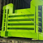 Large green metal equipment secured in a shipping container