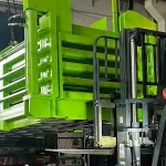 Forklift moving bright green industrial equipment.