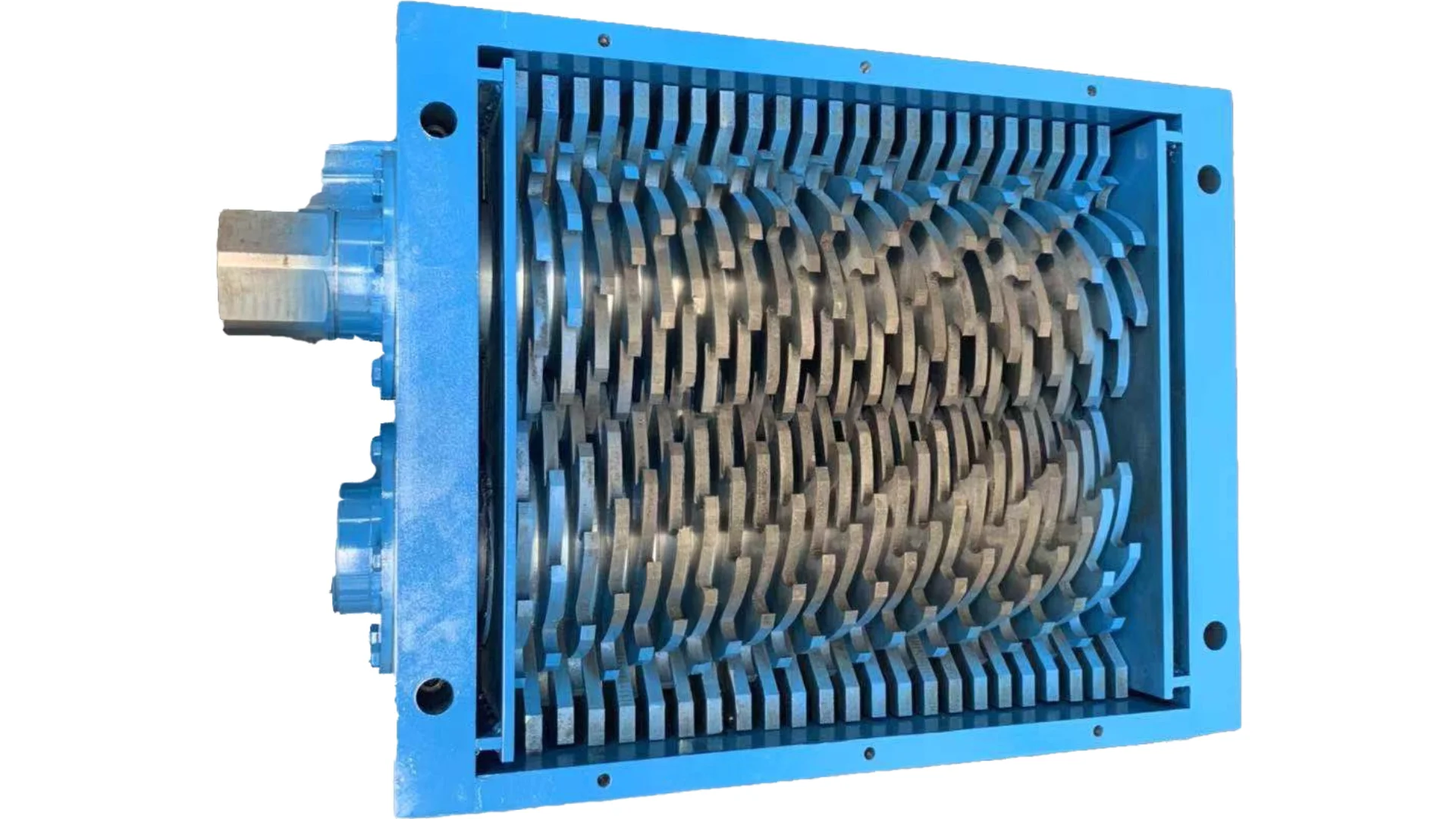 A imagem mostra um tipo de trituradora industrial, especificamente uma trituradora rotativa. Esta máquina possui um conjunto de lâminas contra-rotativas com dentes em forma de gancho que são projetadas para puxar o material para dentro da câmara de corte, triturando eficazmente e reduzindo o tamanho do material processado. A moldura azul ao redor do triturador indica a construção resistente típica desse equipamento, usado para fins de reciclagem ou gerenciamento de resíduos, como processamento de plásticos, metais ou resíduos em fragmentos menores.