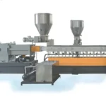 an advanced twin-screw compounding pelletizing line used for versatile polymer processing. The equipment features multiple sections including two large metal hoppers at the top for feeding materials, a lengthy horizontal twin-screw mechanism for blending and extruding polymers, and a pelletizing unit at the end where the processed polymers are cut into pellets. The machinery is mounted on a sturdy, orange and black metal frame, with various motors and control units visible. The background is a plain light gray, highlighting the industrial machinery.